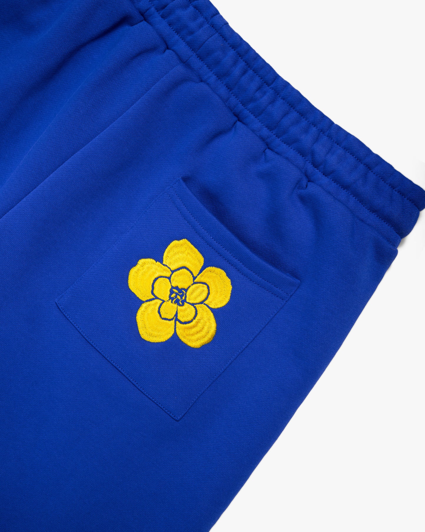 Close-up of the back pocket on blue shorts, featuring floral embroidery for a unique touch.