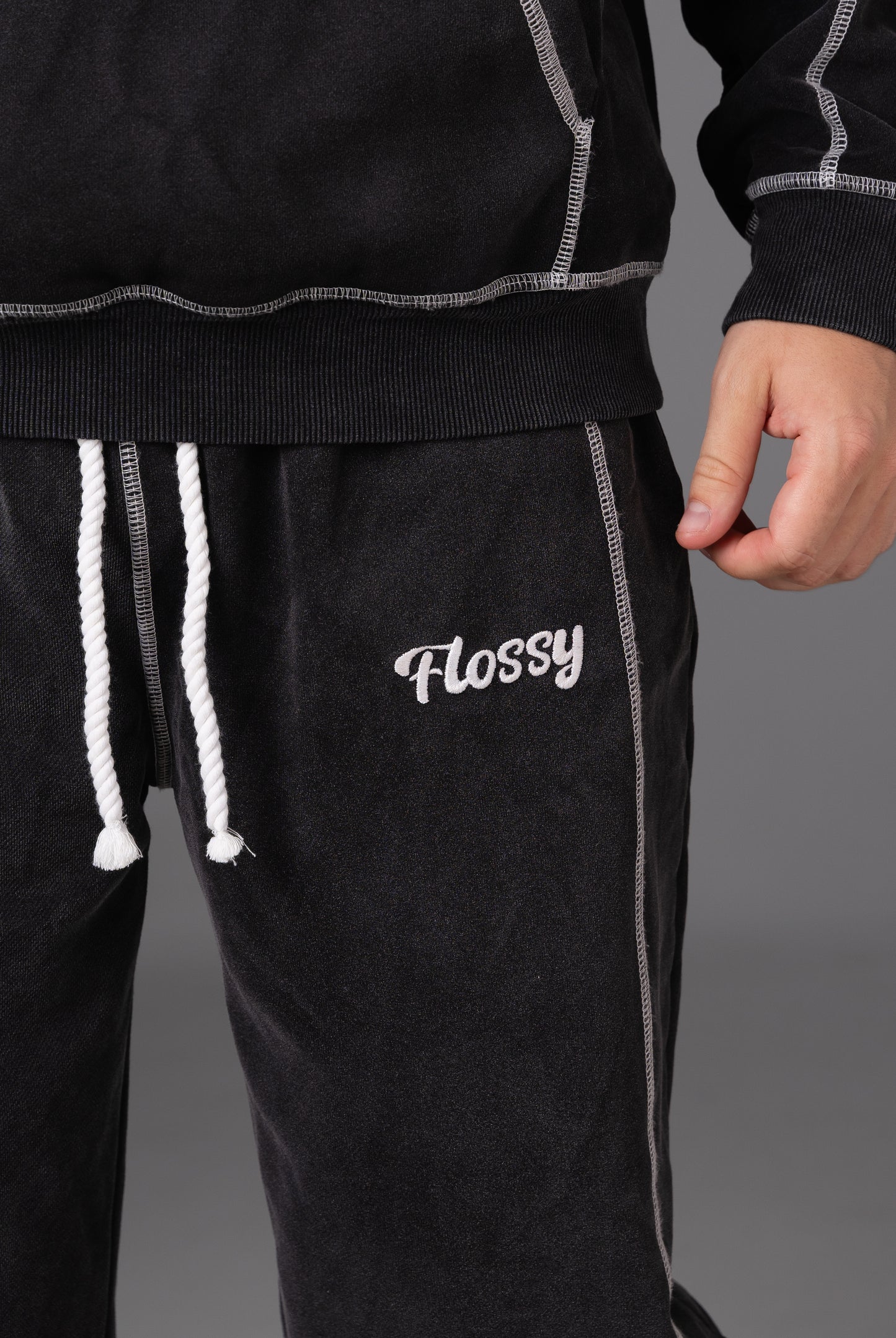 Closeup of embroidered Flossy logo on acid wash black joggers