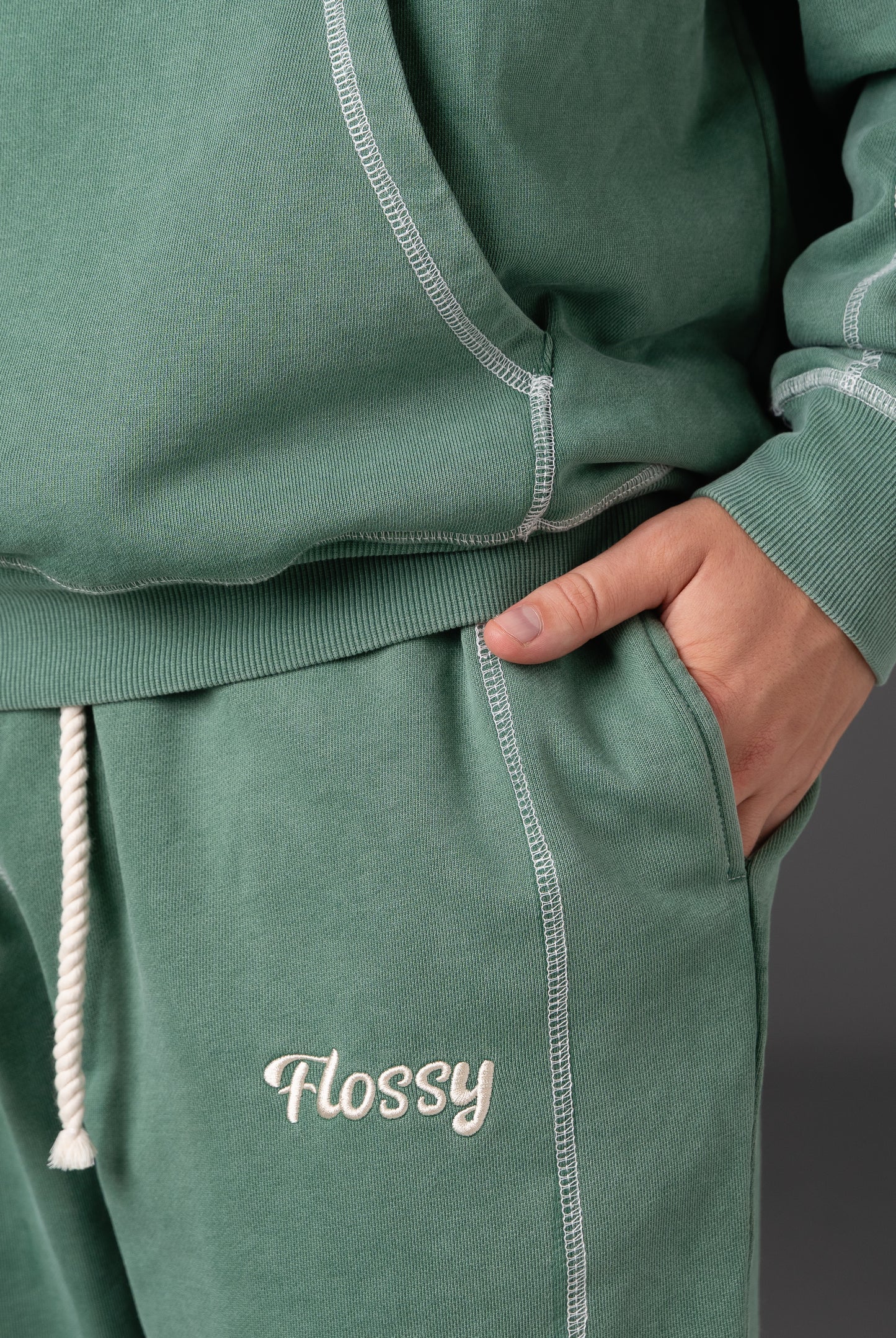 Closeup of embroidered Flossy logo on acid wash green joggers