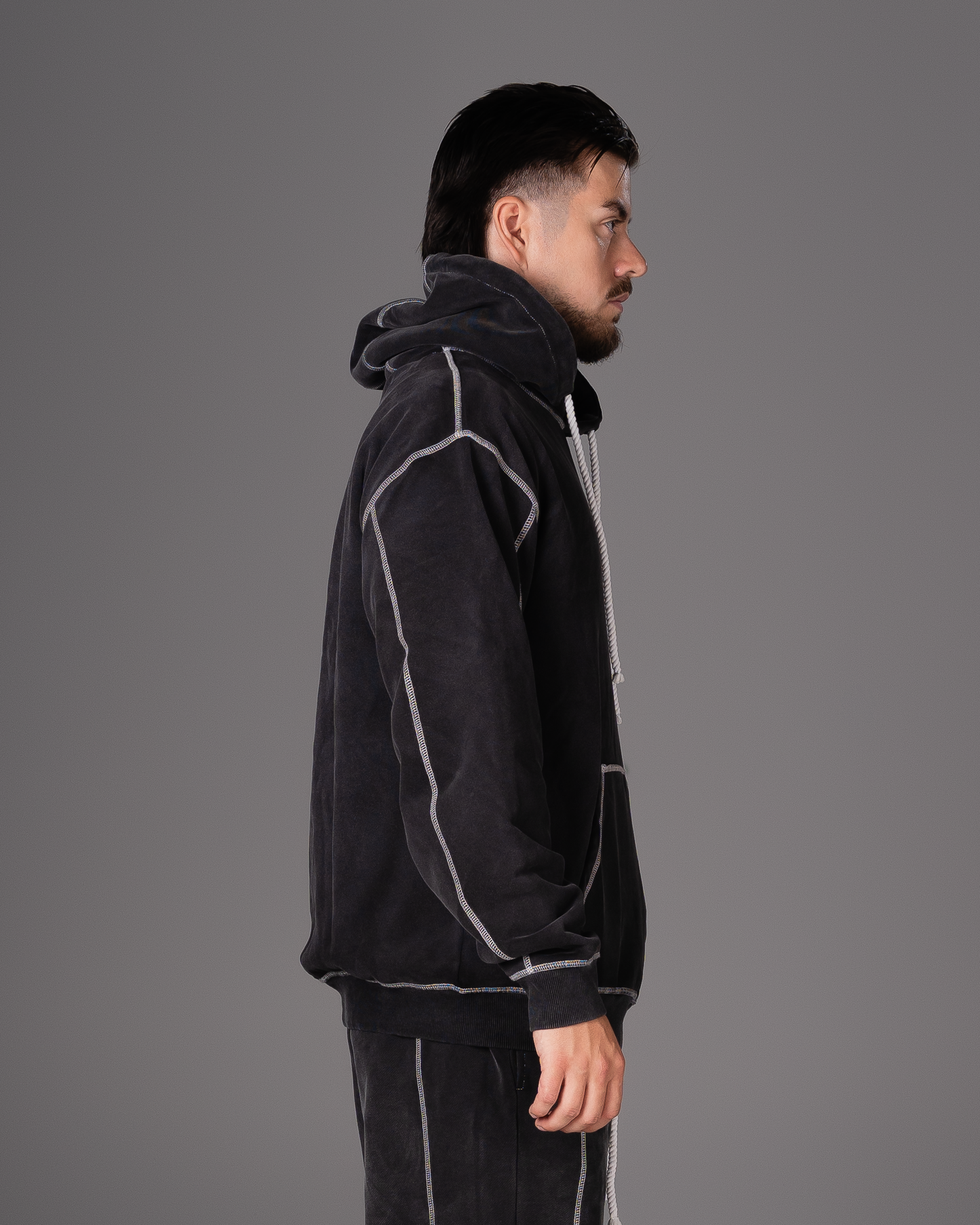 Flossy acid wash black hoodie, side profile highlighting stitching and fit